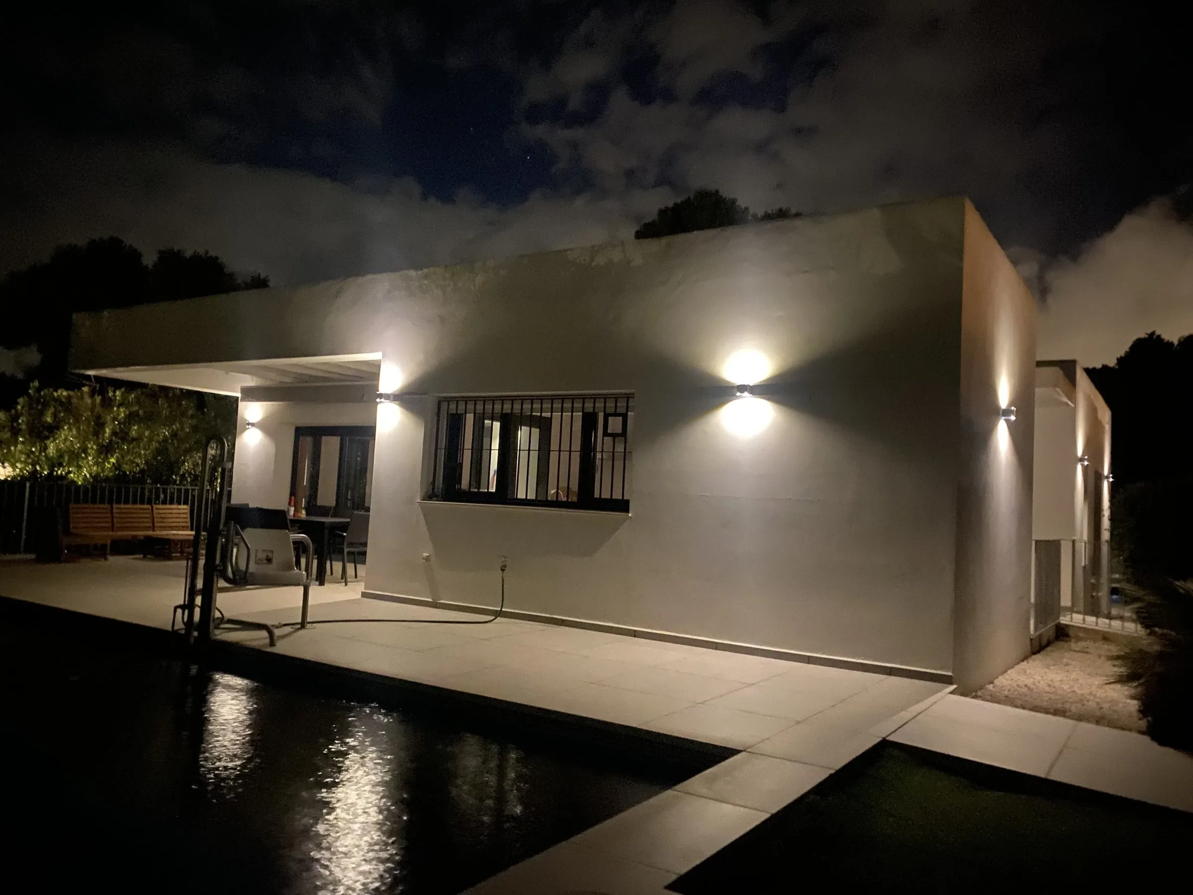 The villa lit up at night, with the step-free terrace, the pool hoist and the pool in front
